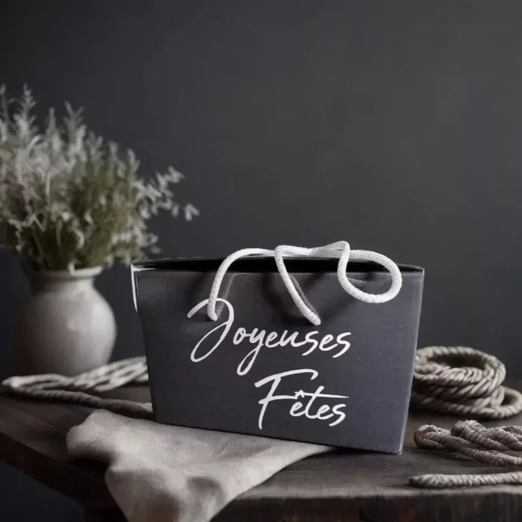Sac-cadeau noir avec écrit dessus "Joyeuses Fêtes"